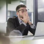 Tired young man holding a laptop in the office