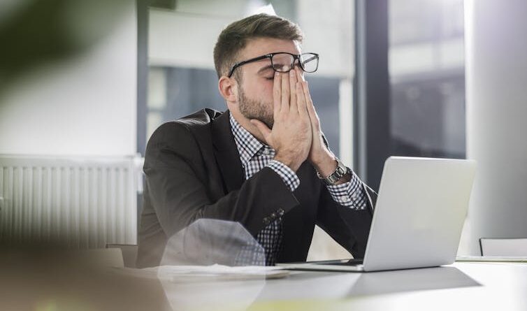 Tired young man holding a laptop in the office