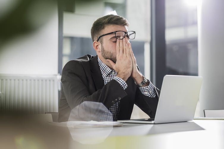 Tired young man holding a laptop in the office